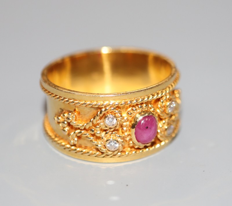 A modern yellow metal, cabochon ruby and diamond set band, with ropetwist decoration, size P, gross 6.1 grams.